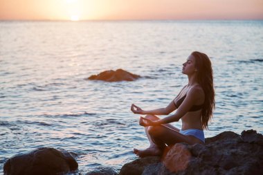 Lotus pozisyonunda bir bayan. Meditasyon ve tefekkür. Yalnız zaman ve rahatlama konsepti. Doğa manzarası, kopyalama alanı