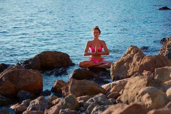 Egyedül voltam. Meditáció és önimádat. Nyugodt hölgy rózsaszín bikiniben meditál a sziklán. Nyugodt tenger. Szabadidő a szabadban — Stock Fotó