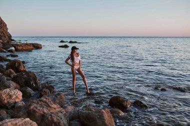 Denizde taş üstünde poz veren kadın. Harika bir deniz manzarası. Nefes kesici deniz manzarası. Güzellik ve rahatlama konsepti. Plaj tatili