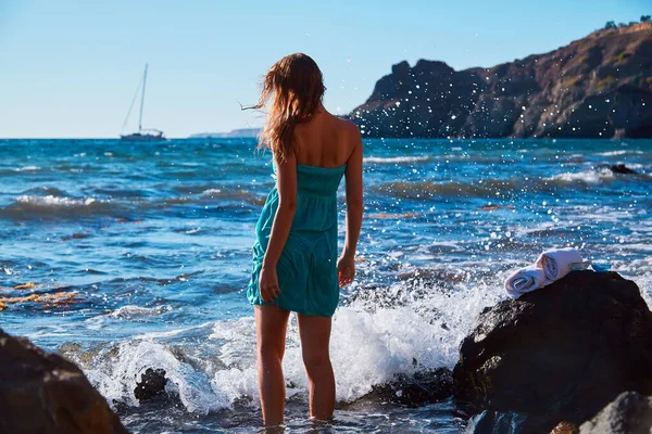 Γυναίκα με μπλε φόρεμα που περπατάει στην ακτή. Βουνό στο βάθος. Φύση και διακοπές στην παραλία. Καλοκαιρινή ώρα και διακοπές — Φωτογραφία Αρχείου