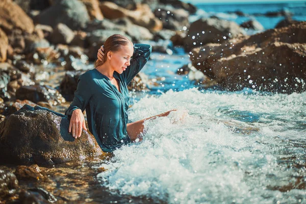 Woman in blue wet dress sitting in crystal sea water. Meditation and time for relax. Summer time and relaxation concept