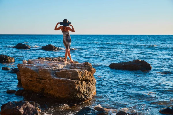 Taş üstünde poz veren bir kadın. Güzel doğa manzarası. Yaz zamanı, plaj tatili ve rahatlama konsepti, kopyalama alanı