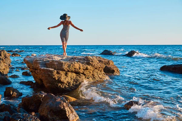 Γυναίκα ντυμένη να χορεύει πάνω σε βράχο. Κύματα πέφτουν πάνω σε πέτρες. Παρθένα φύση, καλοκαιρινές διακοπές και παραλία έννοια. Αντιγραφή χώρου — Φωτογραφία Αρχείου