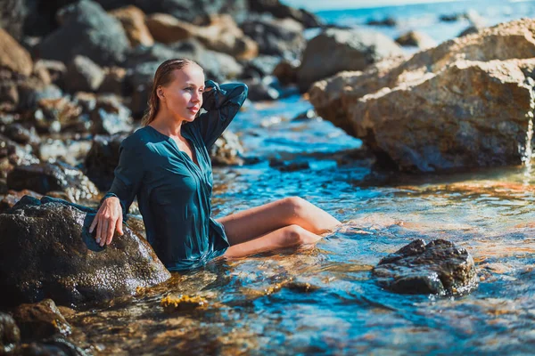Καλοκαιρινή ώρα και αίσθηση χαλάρωσης. Γυναίκα με μπλε βρεγμένο φόρεμα κάθεται σε κρυστάλλινα νερά. Διαλογισμός και χρόνος για χαλάρωση — Φωτογραφία Αρχείου