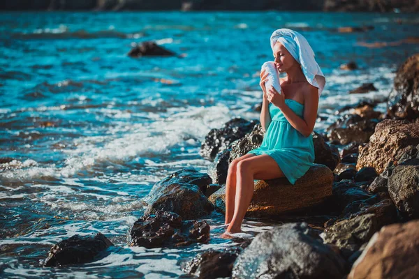Aantrekkelijke vrouw zit op rots in de buurt van kristalheldere zee. Zee spa, ontspanning en schoonheidsdag. Ontspanning en zomertijd — Stockfoto