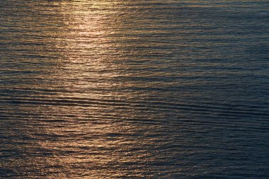 Güneş ışınları okyanusa düşüyor. Sakin denizin üzerinde gün batımı. Su dokusu ve altın saat. Yaz zamanı ve bakire doğa konsepti
