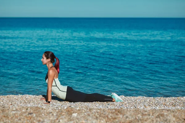 Dama haciendo yoga al aire libre. Posición sosteniendo el cuerpo en los brazos. Vista al mar y la naturaleza. Concepto de tiempo de deporte y estiramiento — Foto de Stock