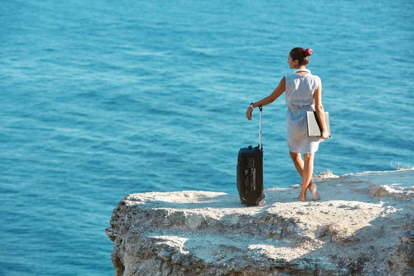 带着手提箱和手提电脑站在海岩上的女商人。生活方式的改变，自由职业的想法。远程工作概念 — 图库照片