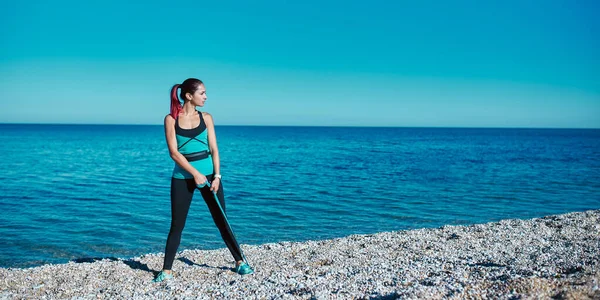 A lány félrenéz, pózol a tengeren. Trendi kényelmes sportruházat és gumiszalag. Fitness és sport ötlet, másolás tér — Stock Fotó