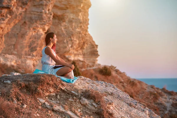 A lány ül a sziklán és élvezi a természetet. Naplemente és friss levegő. Önmagába szívott és elmélkedés idő ötlet, másolás tér — Stock Fotó