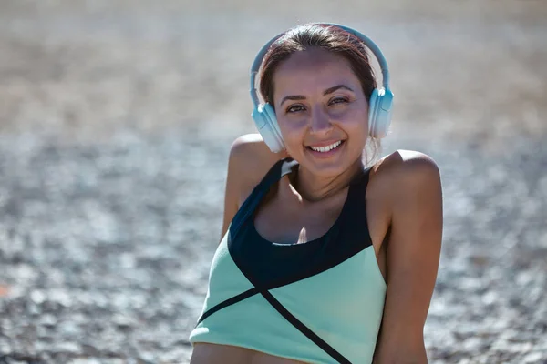Feliz linda mujer escuchar música. Chica en la costa rocosa. Ropa deportiva cómoda para el deporte. Idea de contemplación y fitness — Foto de Stock