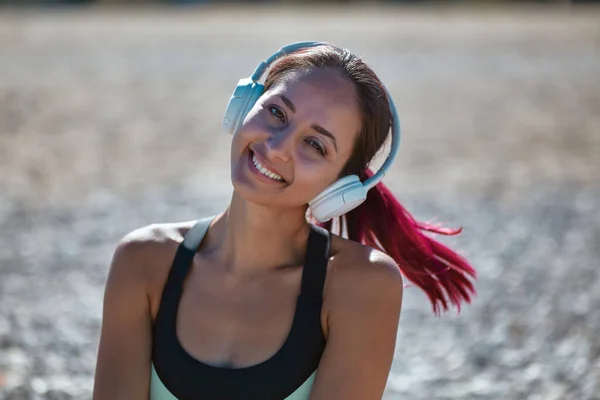 Mujer sonriente posando con auriculares blancos. Señora disfrutando de la música en la playa. Contemplación y concepto de estilo de vida saludable — Foto de Stock