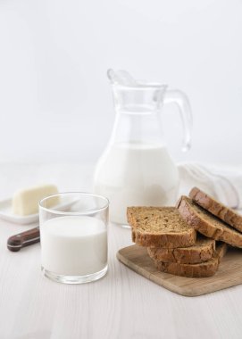 Bir kesme tahtası ile cam sürahi süt ve cam ve küçük bir plaka üzerinde peynir ekmek. Seçici odak. Bulanıklık