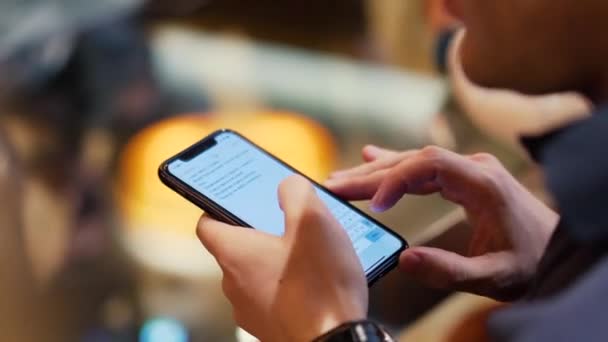 Mladí bokovky chlap SMS s jeho mobilním telefonem na baru. V UK. Mladý muž s telefonem v ruce v kavárně — Stock video