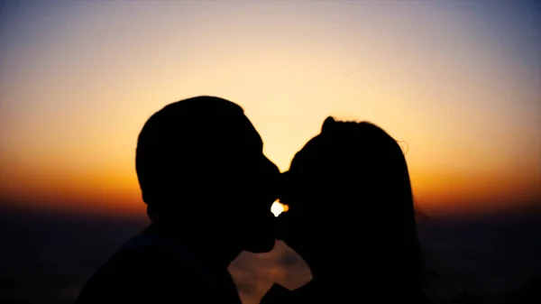 Silhouettes of two lovers kissing by the lake in the evening background. Stock. Peaceful romantic moment — Stock Photo, Image