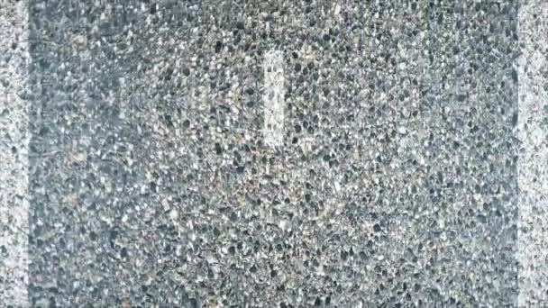 Nahsicht auf eine asphaltierte Straße mit Markierungsstreifen. Nahaufnahme-Animation von Asphalt — Stockvideo