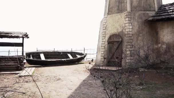 Antiguo edificio con un pozo y un barco. Filmación. Antiguo barco de madera con una casa de una planta, un pozo y una colina en el pueblo cosaco ruso — Vídeos de Stock