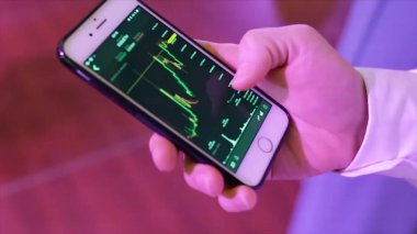 Grafik cep telefonu üzerinde analiz bir işadamı Close-up. Hisse senedi. Yakın çekim kişi el ile grafik ekran üzerinde cep telefonu kullanarak. Cep telefonu grafik arıyor işadamı Close-up