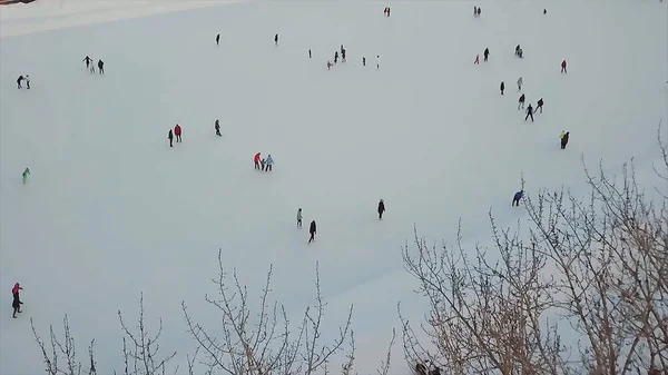 Pista de patinação com muitas pessoas na noite de inverno. Estoque. Vista aérea. Vista aérea na pista de patinação no gelo na praça central da cidade. Muitas pessoas patinam na grande pista escorregadia branca na noite de inverno. Aviação — Fotografia de Stock