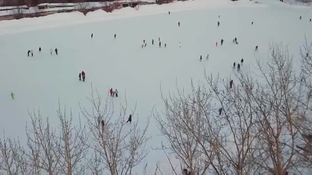 Patinoire avec beaucoup de monde le soir d'hiver. Des actions. Vue aérienne. Vue aérienne sur la patinoire de la place centrale de la ville. Beaucoup de gens patinent sur une grande patinoire blanche glissante la nuit d'hiver. Aérien — Video