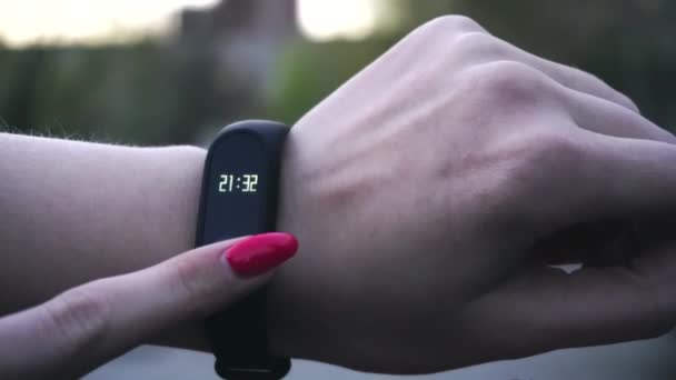 Young woman using wearable fitness tracker. The smart band with display touchpad and heart rate monitor. Entertainment and technology concept. Close-up shot of woman hand with smart watches — Stock Video