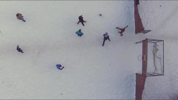 Young guys play football in the winter in the snow-covered field. Stock. Aerial view of a play sport ground in the city. Aerial view of soccer field in winter with snow — Stock Video