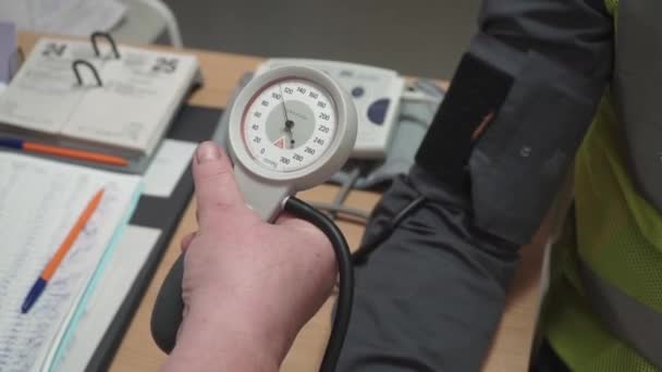Close-up van een arts die maatregelen van de druk van de patiënt. Clip. Mannelijke arts controleren bloeddruk aan jonge man. Polsmeting aan patiënt — Stockvideo