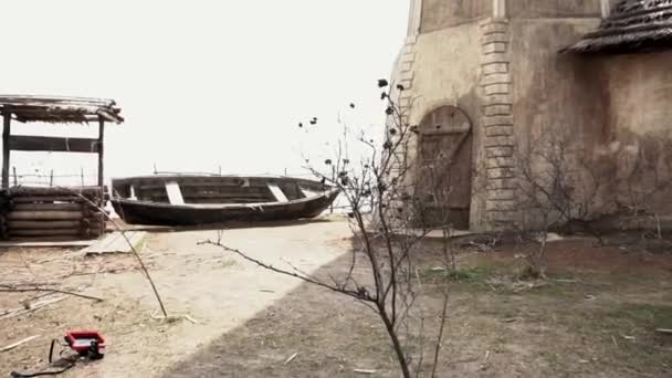 Velho barco de madeira está na margem de um rio de montanha. Filmagem. Velho barco de peixe quebrado em uma costa de areia do mar perto do poço — Vídeo de Stock