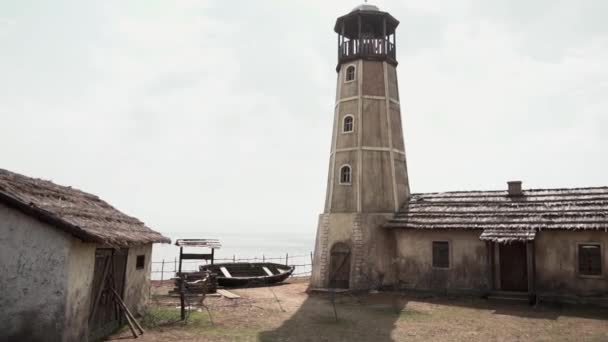 Alter Leuchtturm und altes Boot. Filmmaterial. Leuchtturm und altes Boot am Meer — Stockvideo