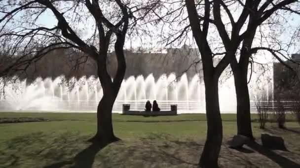 City fountain. Footage. People walking in the park. Fountain in city park on hot summer day. Stream of water, drops and bright splashes of water in beautiful city fountain — Stock Video