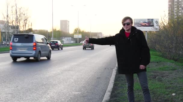 若い男が路上に車を止めると、彼の手を上昇しようとしています。若い男は道端に車を停止します。 — ストック動画