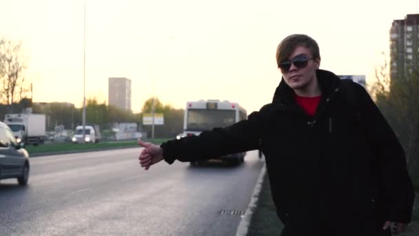 Joven tratando de detener el coche en la calle y levantar la mano. Joven para el coche en el borde de la carretera — Vídeo de stock