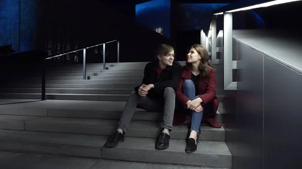 年轻夫妇晚上坐在楼梯上。美丽的夜晚, 在城市里散步 — 图库照片