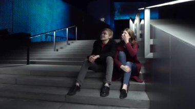 Geceleri merdivenlerde oturan genç bir çift. Şehrin etrafında bir yürüyüş için güzel bir gece
