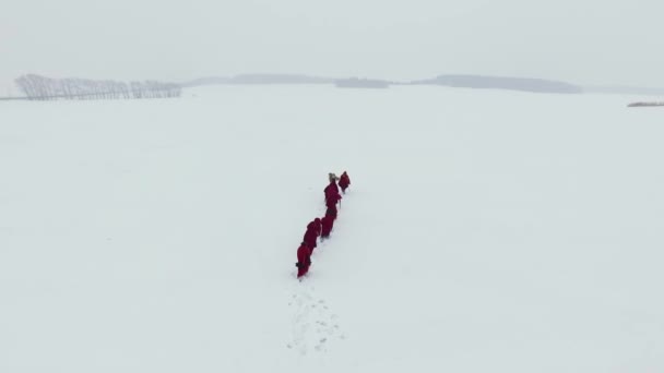 Groep monniken pelgrims in kap gewaad langs wintersneeuw parcours in veld. Beeldmateriaal. Het concept van de eeuwenoude cultuur — Stockvideo