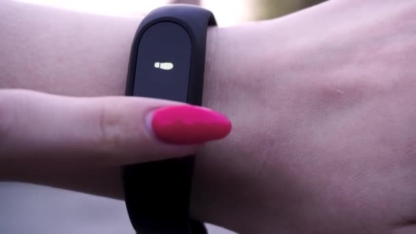 The girls wore a fitness bracelet. Girl checks pulse on fitness bracelet or activity tracker pedometer on wrist, sport, technology and healthy lifestyle concept, close up. Looks at the pedometer — Stock Video