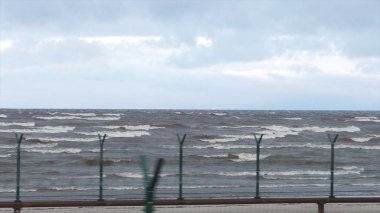 Köpüklü dalgalar fırtına sırasında. Yağmurlu bir gün. Video. Deniz fırtınası. Dalgalar bir çakıl taş Plajı üzerinde haddeleme. Ağır çekim. Deniz suyu. dalga. bir fırtına uyarısı.