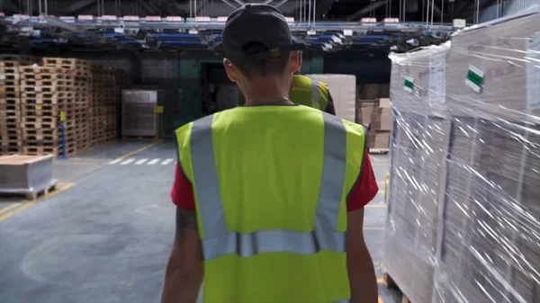 Visão traseira sobre o trabalhador do sexo masculino em colete amarelo andando nas instalações industriais. Clipe. Seguindo tiro de trabalhador industrial em colete amarelo andando através da indústria Manufacturing Factory. Fechar — Fotografia de Stock