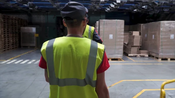 Visão traseira sobre o trabalhador do sexo masculino em colete amarelo andando nas instalações industriais. Clipe. Seguindo tiro de trabalhador industrial em colete amarelo andando através da indústria Manufacturing Factory. Fechar — Fotografia de Stock