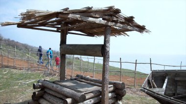 Panoramik manzaralı köy. Eski bir tek katlı ev, bir iyi ve bir tepe ile siyah ahşap tekne harap. Eski ahşap su iyi
