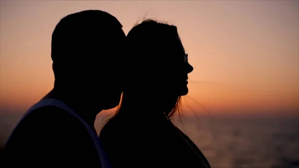 Silhouette coppia baciare su sfondo tramonto. Azioni. Silhouette di amanti romantici abbraccio con mare e bel tramonto. Silhouette di una coppia innamorata su uno sfondo tropicale al tramonto . — Foto Stock