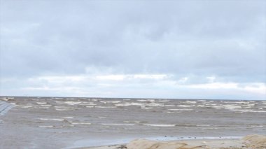 Boş kumsalda, fırtınalı bulutlu gündoğumu skyview haddeleme kıyı dalgalar deniz. Video. Kumlu sahilde dalgalar deniz. Bulutlu gökyüzü gri su ile deniz manzarası. Doğanın gücünü. Yolculuk tutkusu veya seyahat ve