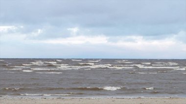 Boş kumsalda, fırtınalı bulutlu gündoğumu skyview haddeleme kıyı dalgalar deniz. Video. Kumlu sahilde dalgalar deniz. Bulutlu gökyüzü gri su ile deniz manzarası. Doğanın gücünü. Yolculuk tutkusu veya seyahat ve