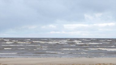 Boş kumsalda, fırtınalı bulutlu gündoğumu skyview haddeleme kıyı dalgalar deniz. Video. Kumlu sahilde dalgalar deniz. Bulutlu gökyüzü gri su ile deniz manzarası. Doğanın gücünü. Yolculuk tutkusu veya seyahat ve