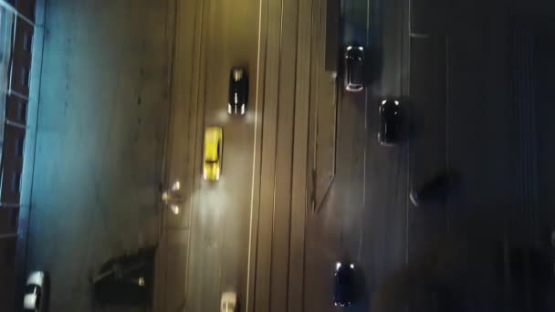 Top Down luchtfoto Drone zicht op een weg met auto's rijden, Clip's nachts. Verkeer op de snelweg richting moderne stad. Koplampen als gevolg. Luchtfoto van het verkeer op de tol op de snelweg. — Stockvideo