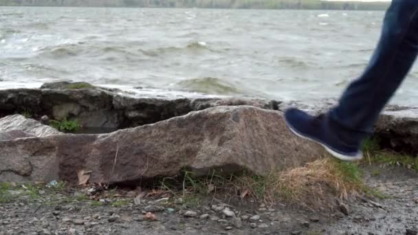 メンズ足は、湖の前に石の上に立っています。水の浸水の石。川でリラックスした男性の足のクローズ アップ。湖の岸に靴メンズ足 — ストック動画