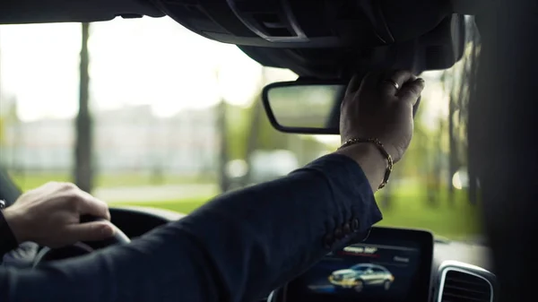 Homme d'affaires conduisant une voiture et regardant dans le rétroviseur. Des actions. Homme d'affaires dans la voiture regardant dans le rétroviseur — Photo