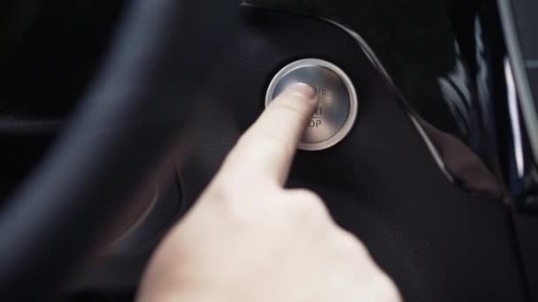 La mano del conductor presiona el botón de parada de arranque del motor. Acciones. detalles interiores del coche crossover de lujo moderno — Vídeo de stock