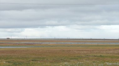 Panorama görüş alanı ve yol ile bulutlu gökyüzü arka plan. Video. Alan ve yol ve dramatik gökyüzü arka plan üzerinde soğuk Sonbahar gökyüzünde ağır gri bulutlar. Yol ve gökyüzü arka plan.