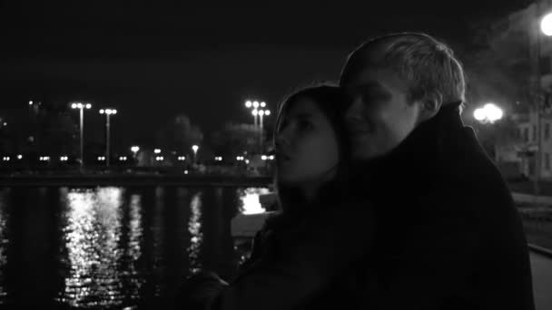 Mladý pár, vášnivě objímat na městské ulici v noci. Mladý pár obejmout a políbit navzájem v city parku. Zblízka střílel. Mladý pár šťastný muž a atraktivní dívka kráčí v noci — Stock video
